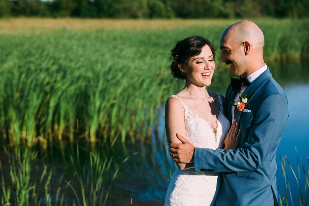 bride and groom portrait with pond and greenery in the background 